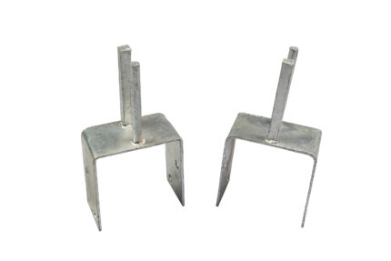 A side-by-side comparison of two galvanized steel Jersey barrier saddle brackets on a white background, showing a dual-peg model on the left and a single-peg model on the right.