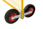 A detailed front-side view of a yellow temporary fence panel supported by a dual-wheel assembly, highlighting the heavy-duty galvanized steel bracket and bolted wheel axles.