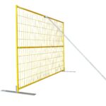 A yellow mesh temporary fence panel installed on flat metal bases and stabilized by a diagonal silver windbrace.